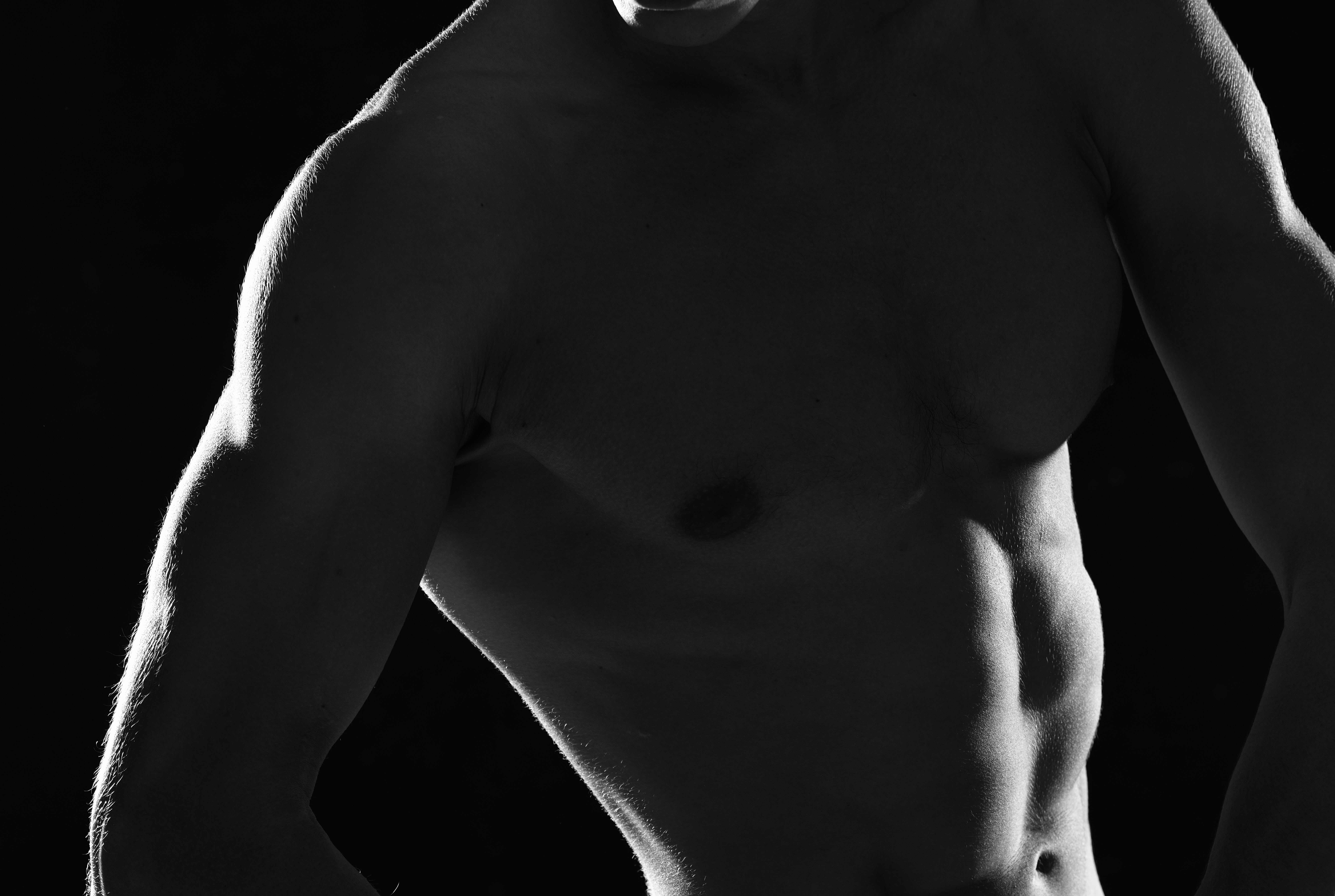 Muscular torso with defined physique against dark background