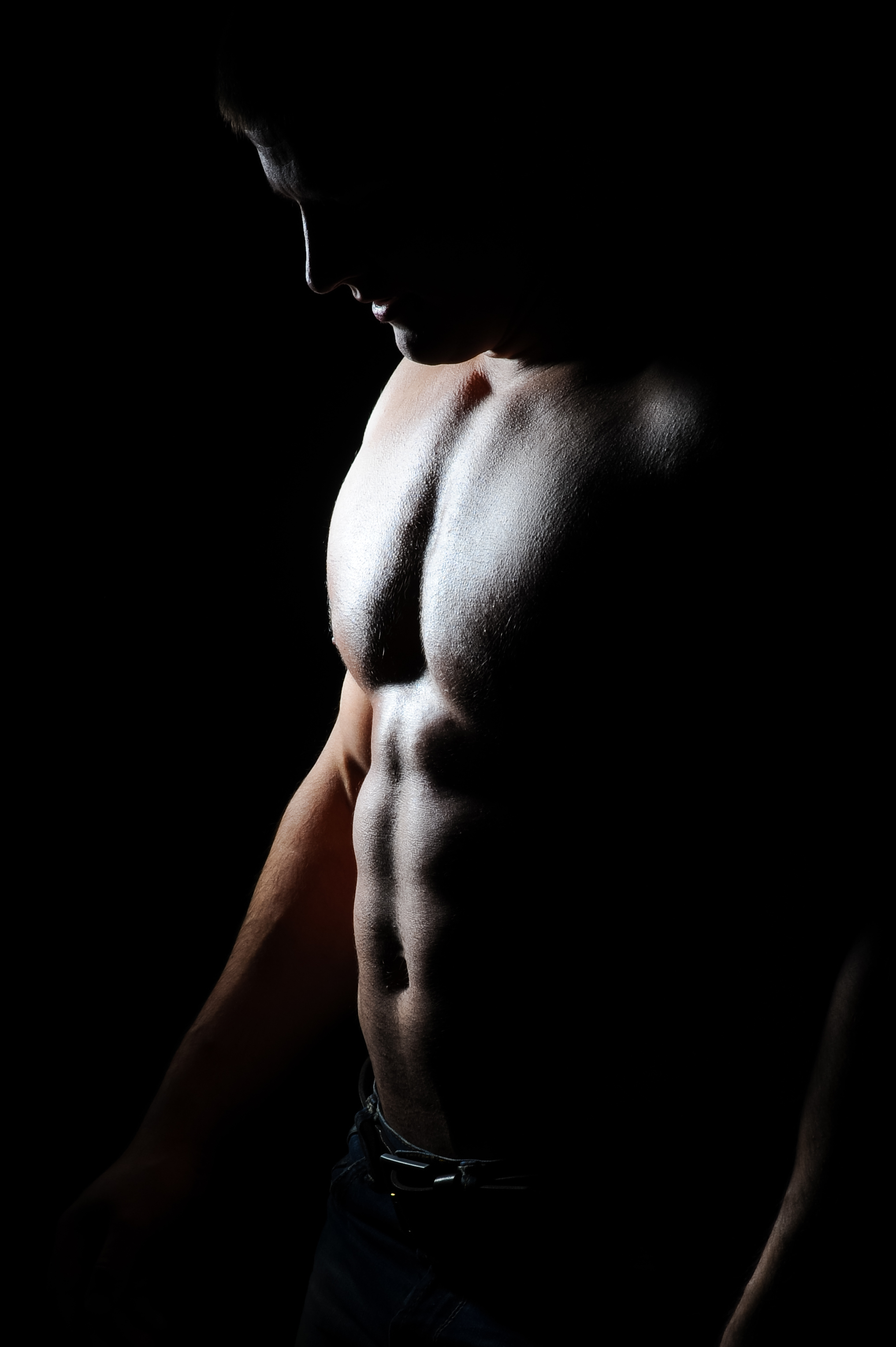 Muscular man with defined abs in a dark, moody setting