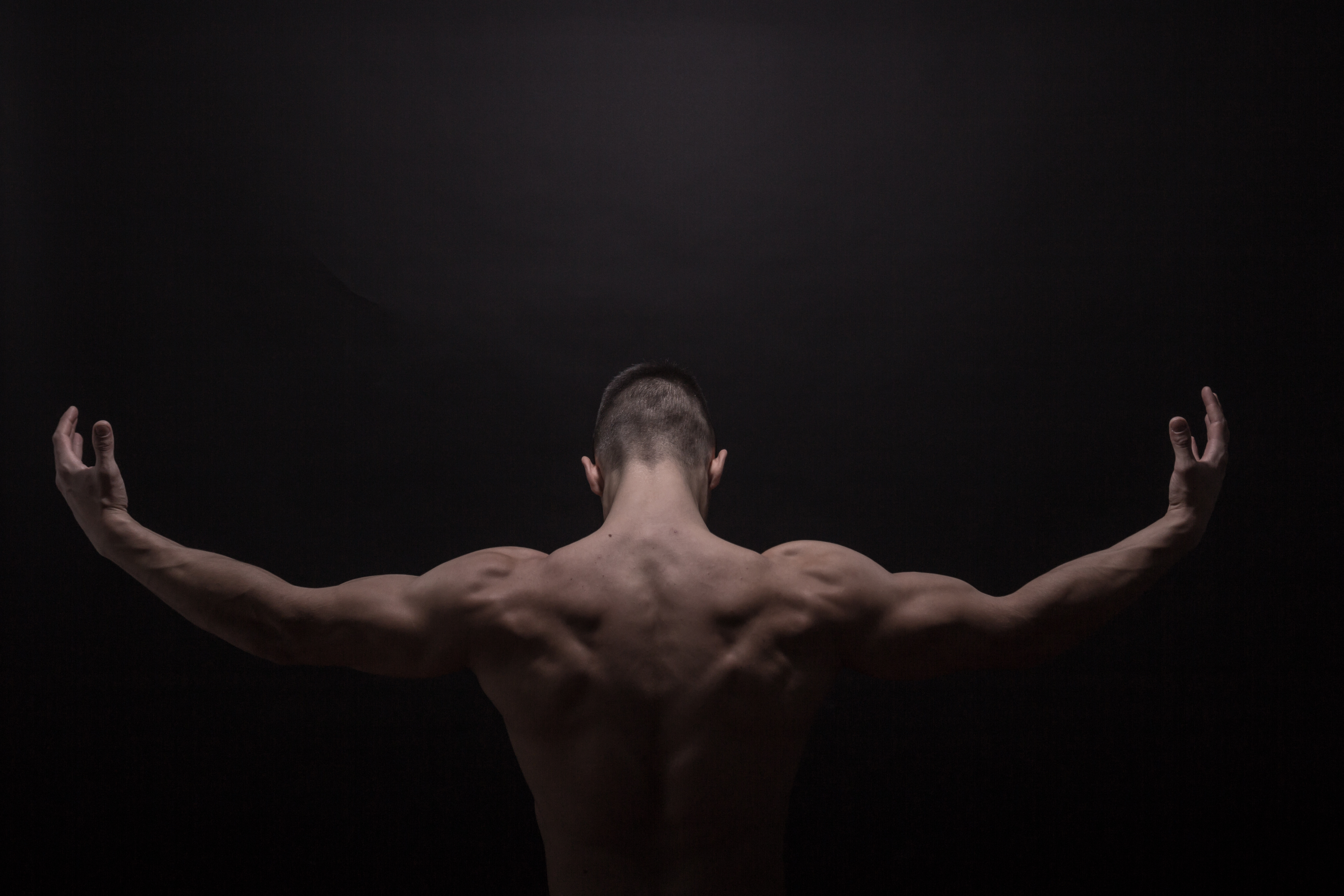 Strong man showing back muscles, rear view - Gegonius mindset and discipline